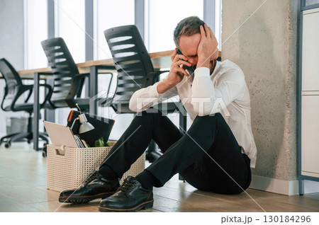 Depressed, sitting on the floor. Unemployed man is with personal belongings after being fired 130184296