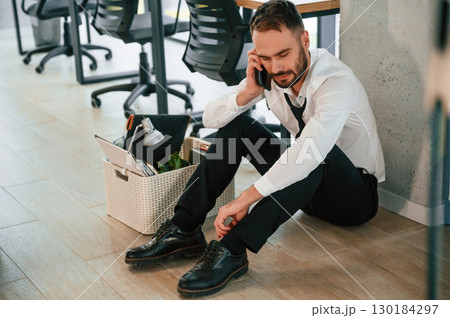 Depressed, sitting on the floor. Unemployed man is with personal belongings after being fired 130184297