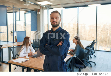 Repairman is standing in the office, employees behind 130184572