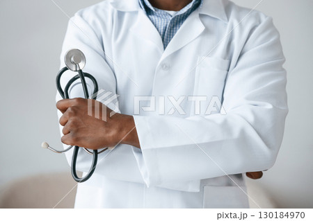 Standing and holding stethoscope. Black man as doctor in the clinic office 130184970
