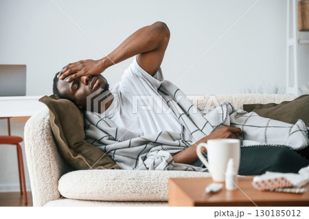 Lying down on the sofa. Sick black man is at home Lying down on the sofa. Sick black man is at home 130185012
