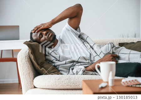 Lying down on the sofa. Sick black man is at home 130185013