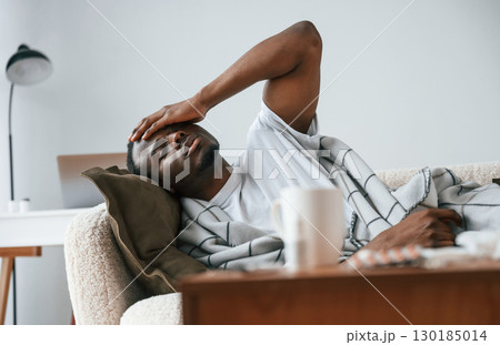 Lying down on the sofa. Sick black man is at home Lying down on the sofa. Sick black man is at home 130185014