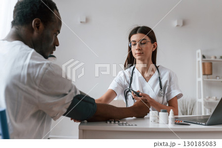 Female doctor measures blood pressure of a man Female doctor measures blood pressure of a man 130185083