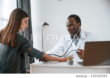 Customer service. A doctor measures a young woman's blood pressure 130185091