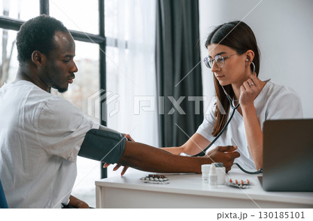 Healthcare conception. Female doctor measures blood pressure of a man 130185101