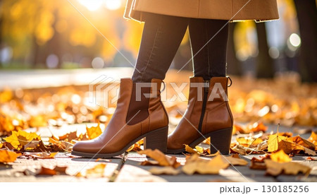 落ち葉の歩道を歩く茶色のレザーアンクルブーツ、温かい秋の光 落ち葉の歩道を歩く茶色のレザーアンクルブーツ、温かい秋の光 130185256