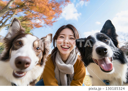秋空の下で笑顔の女性とボーダーコリーたち 130185324