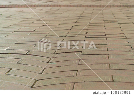 Surface of paved pedestrian sidewalk close-up with perspective stretching into distance with guiding lines of contour shapes of tiles pointing to right direction of movement, hint from above, an omen 130185991