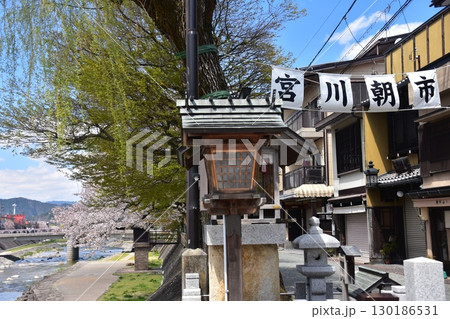 日本の岐阜県の高山市　中心部を流れる宮川と観光名所の宮川朝市　満開の桜と美しい青空　お昼過ぎの様子 130186531