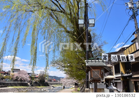 日本の岐阜県の高山市　中心部を流れる宮川と観光名所の宮川朝市　満開の桜と美しい青空　お昼過ぎの様子 130186532