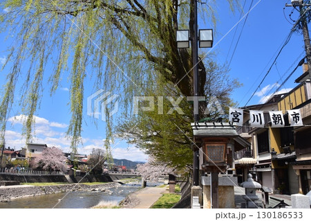 日本の岐阜県の高山市　中心部を流れる宮川と観光名所の宮川朝市　満開の桜と美しい青空　お昼過ぎの様子 130186533