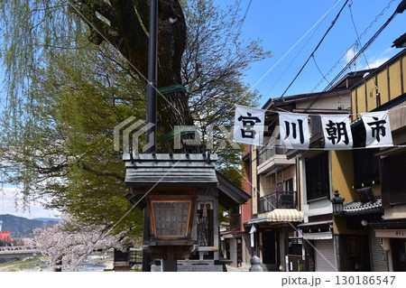 日本の岐阜県の高山市　中心部を流れる宮川と観光名所の宮川朝市　満開の桜と美しい青空　お昼過ぎの様子 130186547