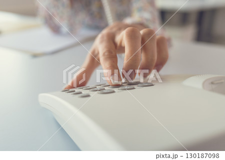 Closeup view of female receptionist dialing a telephone number Closeup view of female receptionist dialing a telephone number 130187098
