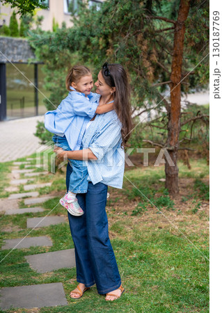 Mother and daughter wearing matching striped shirts and jeans while spending time together outdoors. Concept of family bonding, fashion harmony and casual everyday moments. 130187769