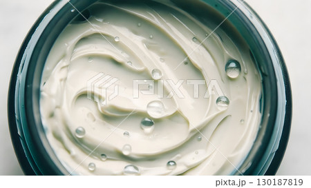 Creamy moisturizer with sparkling droplets in a glass container for skincare routine Creamy moisturizer with sparkling droplets in a glass container for skincare routine 130187819