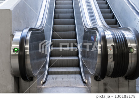 Contemporary escalators with polished metallic steps and bright handrails smoothly ascend within a minimalist public space, symbolizing urban growth and upward mobility Contemporary escalators with polished metallic steps and bright handrails smoothly ascend within a minimalist public space, symbolizing urban growth and upward mobility 130188179
