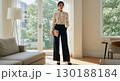洗練された大人の女性｜ナチュラルな光が差し込むリビングで佇むビジネススタイルの日本人女性 130188184