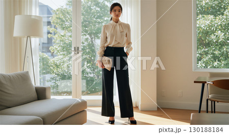 洗練された大人の女性｜ナチュラルな光が差し込むリビングで佇むビジネススタイルの日本人女性 130188184