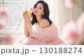 ピンクのドレスを纏い花を持つ女性のエレガントなポートレート 130188274