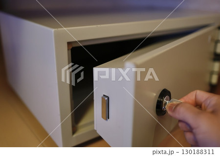 手に鍵を持ち小型金庫を施錠または解錠するイメージ 130188311