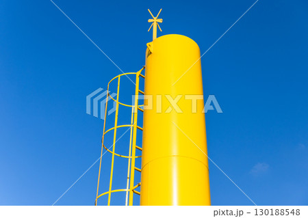 Yellow beacon, a navigation tower with cross shaped top mark is under blue sky 130188548