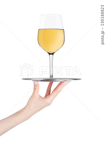Hand holds tray with white wine glass on white 130188823