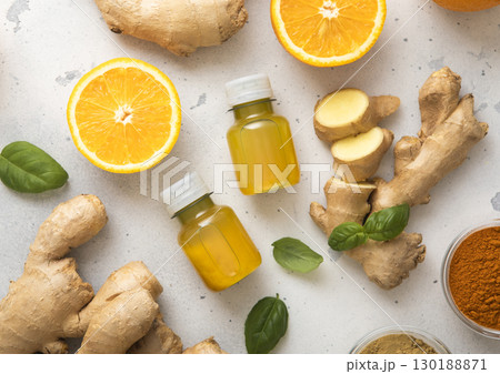 Immune turmeric energy shot drink with fresh raw ginger root and oranges on light background. 130188871