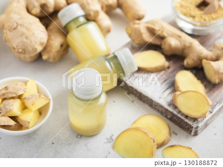 Immune ginger energy shot drink bottles with fresh raw ginger root on light background.Macro. 130188872