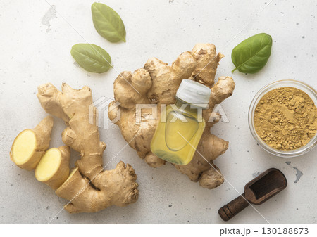 Bottle of immune ginger energy shot drink with ginger root and grounded powder on light background. Bottle of immune ginger energy shot drink with ginger root and grounded powder on light background. 130188873