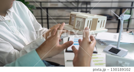 Sustainability in Architecture. Professionals discussing eco-friendly building models and renewable energy solutions. Sustainability in Architecture. Professionals discussing eco-friendly building models and renewable energy solutions. 130189102