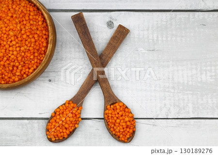Red lentils in wooden bowl on wooden table background. Top view, copy space. Flat lay. Red lentils in wooden bowl on wooden table background. Top view, copy space. Flat lay. 130189276