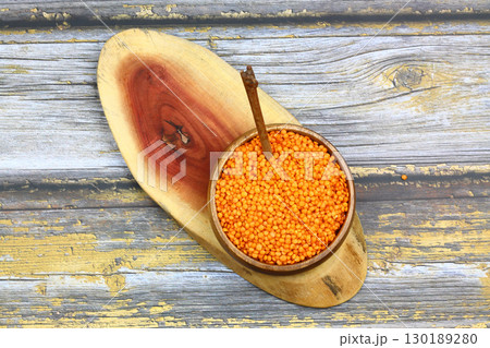 Red lentils in wooden bowl on wooden table background. Top view, copy space. Flat lay. 130189280
