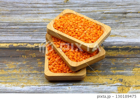 Red lentils in wooden bowl on wooden table background. Top view, copy space. Flat lay. 130189475