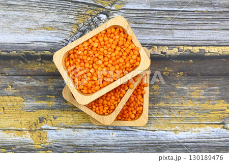 Red lentils in wooden bowl on wooden table background. Top view, copy space. Flat lay. 130189476