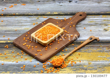 Red lentils in wooden bowl on wooden table background. Top view, copy space. Flat lay. 130189477