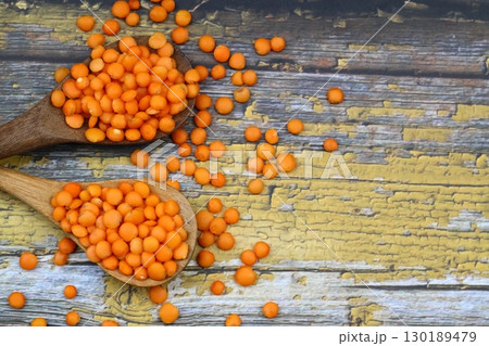 Red lentils in wooden bowl on wooden table background. Top view, copy space. Flat lay. 130189479