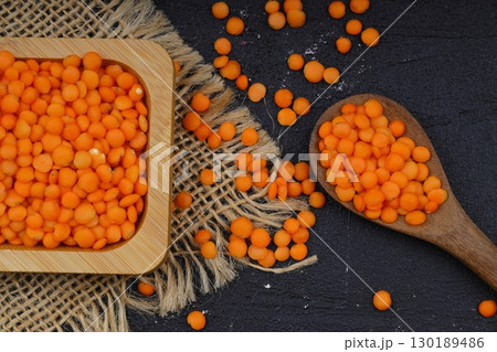 Red lentils in wooden bowl on wooden table background. Top view, copy space. Flat lay. 130189486