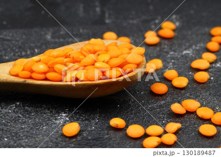 Red lentils in wooden bowl on wooden table background. Top view, copy space. Flat lay. 130189487
