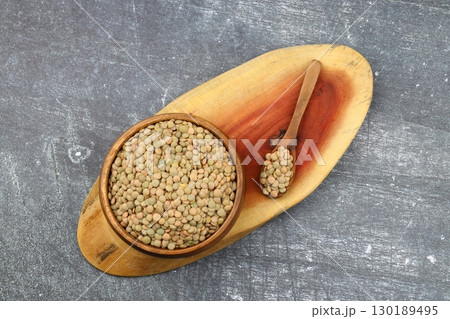 Green lentils in wooden bowl on wooden table background. Top view, copy space. Flat lay. 130189495