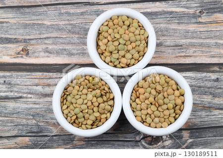 Green lentils in wooden bowl on wooden table background. Top view, copy space. Flat lay. 130189511