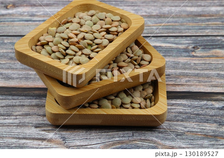 Green lentils in wooden bowl on wooden table background. Top view, copy space. Flat lay. 130189527