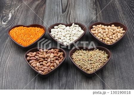 Different type of raw dry legumes composition.   lentils, red lentils, chickpeas and kidney beans. Mix organic legume concept. With Heart shape bowl. 130190018