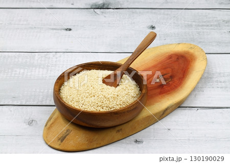 Top view closeup of freshly harvested white sesame in wooden bowl isolated on wooden background with clipping path. 130190029