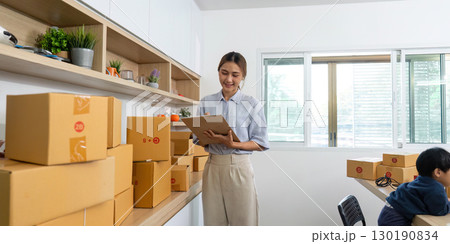 Home Office. A woman managing her online business while holding her child. 130190834