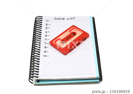 Retro audio cassette tape from the 80s and 90s on a white background. blank playlist on notebook. Top view, nostalgic concept. Retro audio cassette tape from the 80s and 90s on a white background. blank playlist on notebook. Top view, nostalgic concept. 130190859