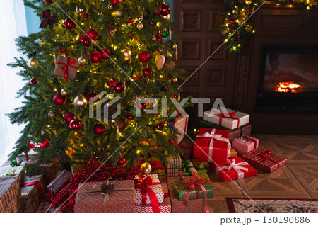Classical Christmas decorated interior living room with fireplace. Christmas tree with red golden ornament decorations gift boxes. Modern classic style interior design apartment. Christmas eve at home Classical Christmas decorated interior living room with fireplace. Christmas tree with red golden ornament decorations gift boxes. Modern classic style interior design apartment. Christmas eve at home 130190886