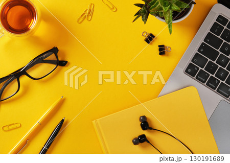 Yellow desk with laptop, notebook, glasses, pens, and earphones. Workspace with copyspace. Yellow desk with laptop, notebook, glasses, pens, and earphones. Workspace with copyspace. 130191689