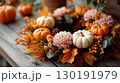Festive Thanksgiving wreath adorned with autumn leaves and pumpkins on a rustic wooden table 130191979