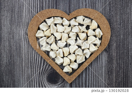 handmade manti (turkish ravioli type dumplings) on wooden heart shape bowl, before cooking 130192028